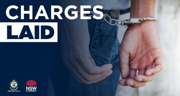 a person is being led in handcuffs by a police officer into a courtroom for a bail hearing in new south wales. the individual is seeking release from custody while awaiting trial for their hearing for their criminal charges through a process known as a bail application 